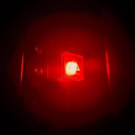 close up view of a button with bright red light shining in the dark background