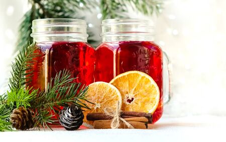 Two cans with a handle with red mulled wine on a white with a garland.の写真素材