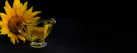 sunflower oil poured into glass saucepan. nearby flowers on a black background. space for text, bannerの写真素材