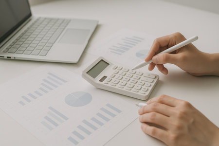 woman hand working with finances about cost and calculator and laptop computer on white tableの素材