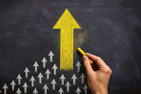Hand drawing yellow arrow on blackboard with chalk, business success conceptの素材