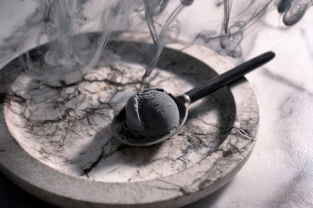 ice cream in a silver spoon on a marble plate with smoke.の素材