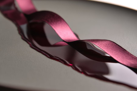 Curly satin ribbon on a black plate, close-upの素材