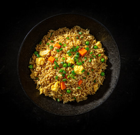 Fried rice with vegetables in a black bowl on a black backgroundの素材