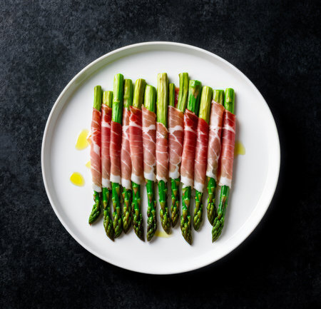 Green asparagus with prosciutto on a white plateの素材