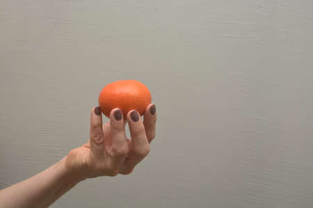 Female hand holds orange citrus fruit. Photo about healthy diet. Human fingers offers vitamin diet food.の写真素材