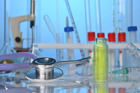 Medical lab desk with chemical glassware and stethoscope. Test tubes, fluid flasks, medical gadgets in chemical laboratory. Biotech research laboratory with biochemicals on the desk. Science center.の写真素材