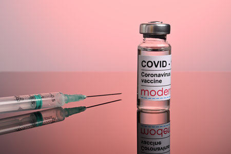 Krasnoyarsk, Russia. April 27, 2021. Moderna Covid-19 vaccine phial with syringe ready for inoculation. Red gradient background. Covid protection illustrative editorial photo for vaccine ads.のeditorial素材