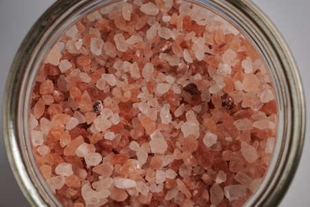 Rose salt crystals inside glass petri dish. Pink Himalayan salt for cooking. Himalayan rock coarse...