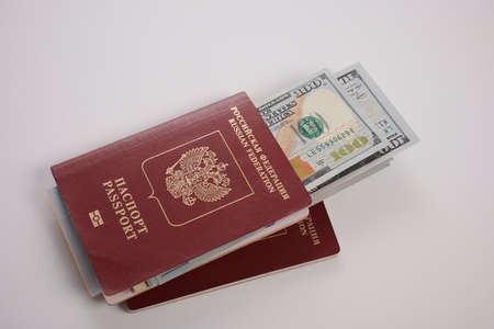 Russian passports with dollars. Dollars are required to trip from Russian to other countries. American money inside Russia ID documents. Cash is universal pass. Legal international papers for travels. Money and identity pass for voyage.の写真素材
