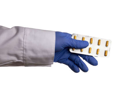 Pharmacist hand offers blister with yellow pills - isolated photo on a white background. Healthcare specialist offers yellow pills of medicaments in the hand. Concept of medical ads for drug stores.の写真素材