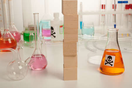 Vertical wooden cubes with toxic substances - labs photo. Template and copyspace on wooden blocks. Any word can be placed on 6 wood modules. Colored poison liquids inside chemical flasks, retorts.の写真素材