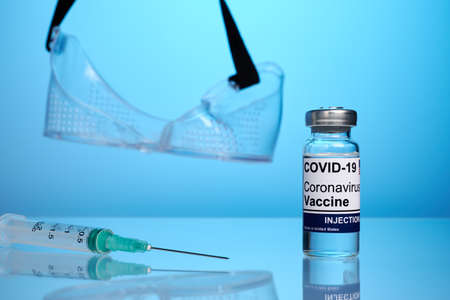 Covid vaccine set and eye protective mask - labs photo. Covid-19 treatment vial on a glass surface...
