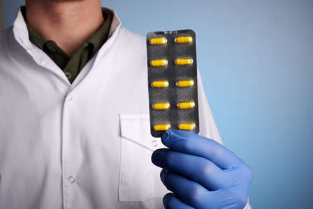 Doctor shows blister of yellow pills. Apothecary guy offers painkiller drugs. Medic practitioner...
