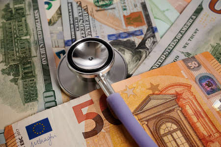 Stethoscope - photo on dollar and Euro banknotes. Medical stethoscope is laying on money bank notes....