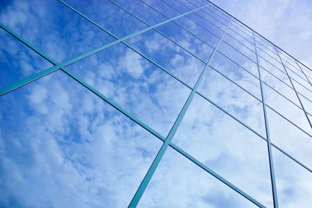 reflections of clouds and blue sky in facade of office buildingの写真素材