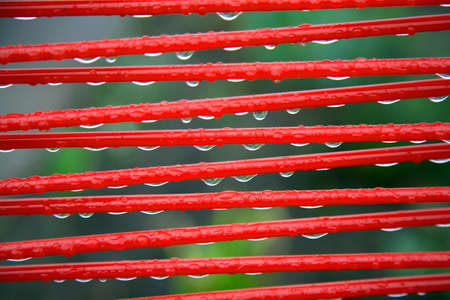 part of red summer chair with raindrops and green backgroundの写真素材