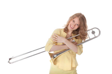 young woman in yellow holding trombone and white backgroundの写真素材