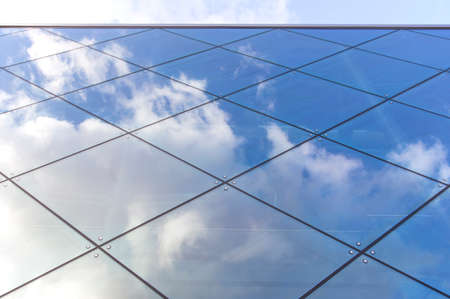 reflexions of clouds and blue sky in glass facade of modern buildingの写真素材