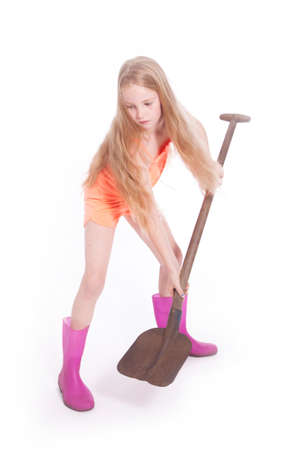 young blond girl working with shovel in studio against white backgroundの写真素材