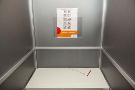 in het aluminium stemhokje met rood potlood