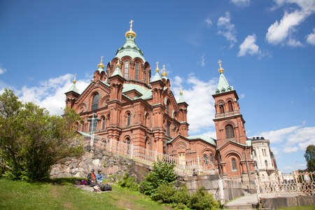 couple enjoying the sun near uspenski cathedral on rock in finnish capital helsinkiのeditorial素材