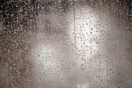 very wet window full of raindrops during downpoarの写真素材