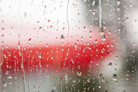 rain on window pane with a lot of red in the backgroundの写真素材