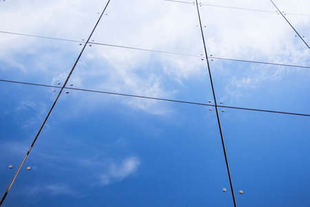 glass panes on facade of trade building reflecting blue sky and cloudsの写真素材