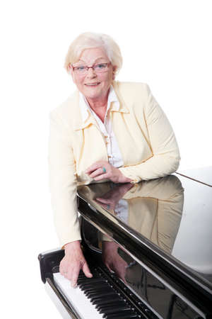 elderly lady in yellow at the piano in studio with white backgroundの写真素材