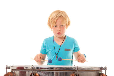 young boy playing kettle drum against white background in studioの写真素材