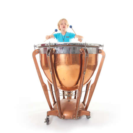 young boy playing kettle drum against white background in studioの写真素材