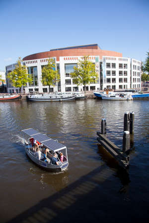 small boat in river amstel in front of opera house in amsterdamのeditorial素材