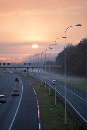 fog and rising sun in the morning on highway A28 near Utrecht De Uithof