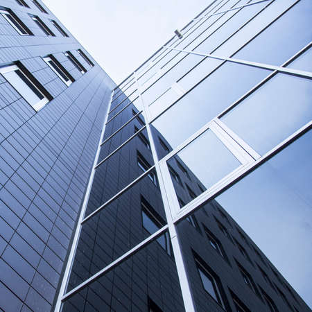facade of office building and reflections of blue sky with clouds