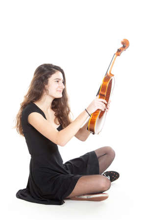 teenage girl holds violin in studio with white backgroundの写真素材