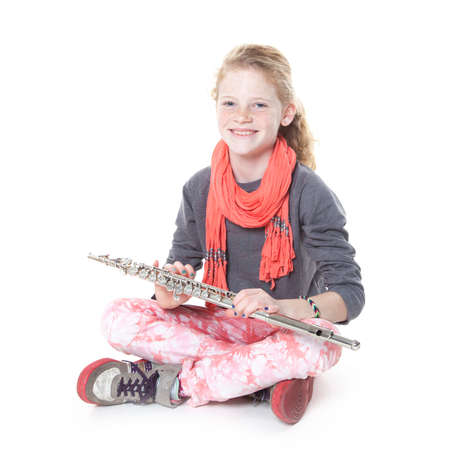 young girl with red hair and freckles with flute in studio against white backgroundの写真素材
