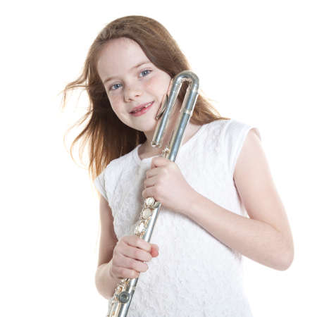 young girl with red hair and missing teeth holding flute in studio against white backgroundの写真素材