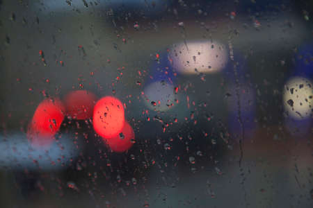 red lights of traffic seen through wet windshield during rainfallの写真素材
