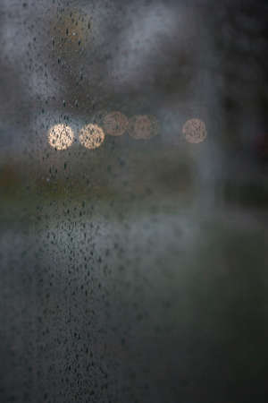 lights of traffic seen through wet windshield during rainfall in the darkの写真素材