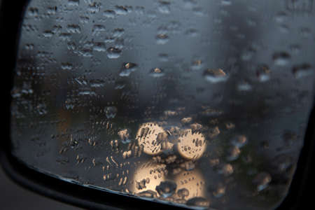 drops on rear view mirror of car and reflections of car lightsの写真素材