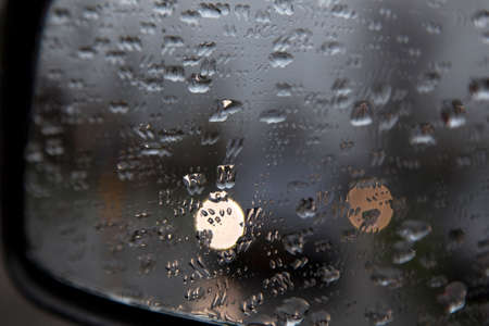 drops on rear view mirror of car and reflections of traffic lightsの写真素材