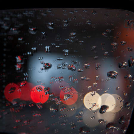 drops on rear view mirror of car and reflections of red and white lightsの写真素材