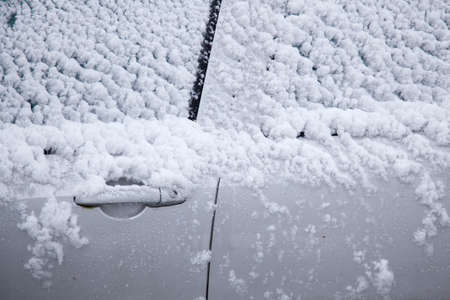 snow on door and windshields of grey carの写真素材