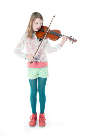 young girl stands in studio against white background and plays the violinの写真素材
