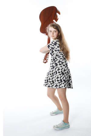 smiling teenage girl in dress swings guitar in studio with white backgroundの写真素材