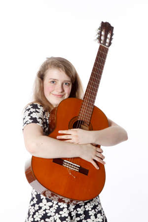 smiling teenage girl in dress holds guitar in studio with white backgroundの写真素材