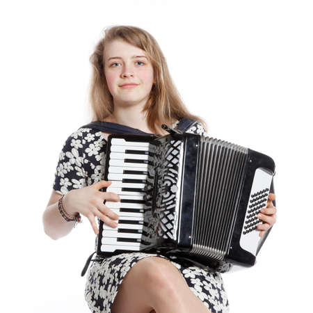 teenage girl sits in studio with accordion against white backgroundの写真素材