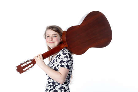 teenage girl in dress holds guitar on shoulder in studio with white backgroundの写真素材