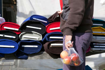 person holding bag of apples while testing fabric on marketの写真素材
